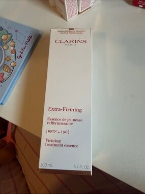 Clarins Extra-Firming Treatment Essence – White with Red Text